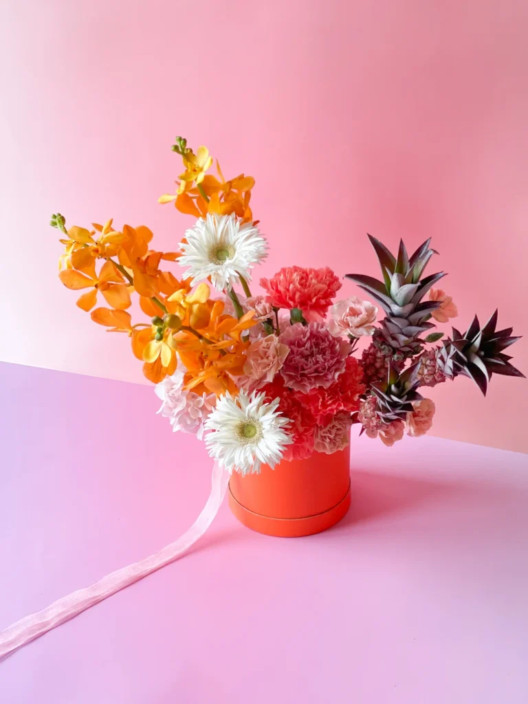 Arranjo de flores exóticas em caixa cilíndrica laranja, Flora Rara pelo Sabiá Estúdio no Porto